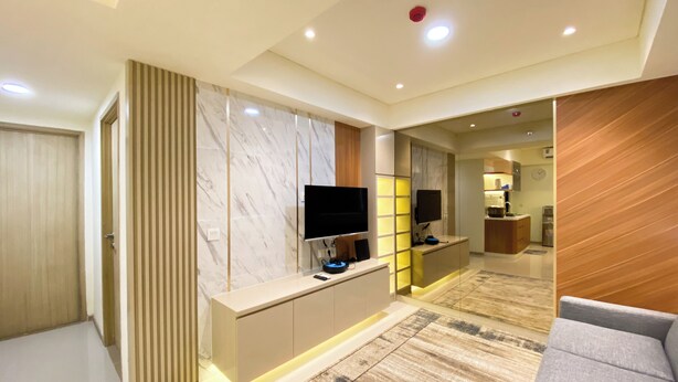 A modern living room with a flat-screen TV, a console table, and a sofa. - Comfortable Designed And Best Deal 2Br At Meikarta Apartment (Cikarang)