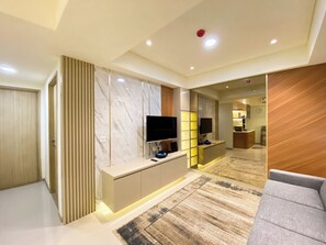 Un salon moderne avec un téléviseur à écran plat, une console et un canapé.