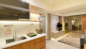 A modern kitchen with a built-in oven, a sink, and a countertop with a dish rack. - Comfortable Designed And Best Deal 2Br At Meikarta Apartment (Cikarang)