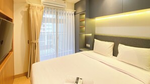 A hotel room with a bed, curtains, an air conditioning unit, and a television. - Comfortable Designed And Best Deal 2Br At Meikarta Apartment (Cikarang)