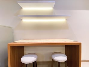 Quarto moderno com mesa de madeira e dois banquinhos estofados.