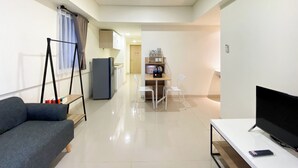 Una sala de estar moderna con un sofá, un televisor y un comedor con sillas y una mesa.