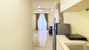 Un pasillo estrecho que conduce a una habitación con kitchenette, un refrigerador y un lavamanos.