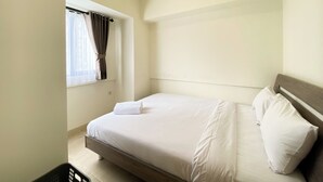 Un dormitorio con cama, ventana con cortinas y una lámpara en el techo.