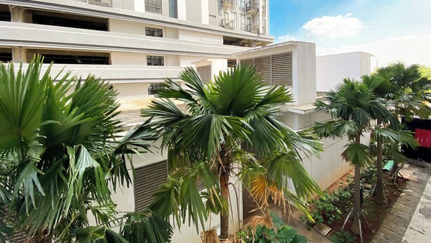 A modern building with multiple balconies and a rooftop garden with palm trees. - Cozy Stay Studio (No Kitchen) Elvis Tower Apartment (Cikarang)