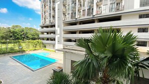 A multi-story residential building with a swimming pool and lush greenery. - Cozy Stay Studio (No Kitchen) Elvis Tower Apartment (Cikarang)