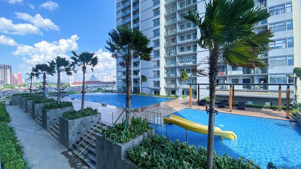 A modern apartment building with a rooftop pool, surrounded by palm trees and greenery. - Brand New And Comfy Studio At Daan Mogot City Apartment (Jakarta)