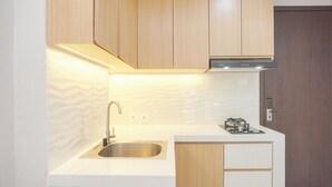 A modern kitchen with wooden cabinets, a stainless steel sink, and a built-in stove. - Brand New And Comfy Studio At Daan Mogot City Apartment (Jakarta)