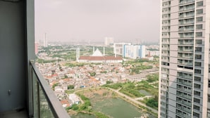 A high-rise building overlooking a cityscape with a mix of residential and commercial buildings, a prominent white-roofed structure, and a river.