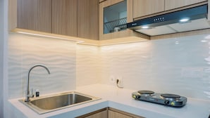 A modern kitchen with a stainless steel sink, wooden cabinets, a built-in oven, and a white countertop.