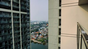 A high-rise building with multiple balconies overlooking a river and a town. - Pleasurable And Tidy Studio Daan Mogot City Apartment (Jakarta)