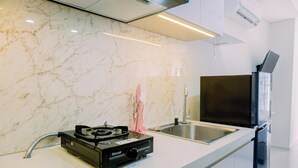 A modern kitchen with a marble backsplash, stainless steel appliances, and a built-in oven. - Pleasurable And Tidy Studio Daan Mogot City Apartment (Jakarta)