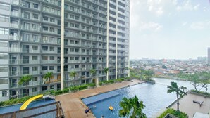 A high-rise building with a swimming pool and a view of a cityscape. - Pleasurable And Tidy Studio Daan Mogot City Apartment (Jakarta)