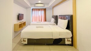 Habitación de hotel con dos camas, un televisor en un estante y un equipo de aire acondicionado en el techo.