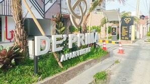 Un letrero de De'Prima Apartments con un logotipo en forma de corazón, una escalera y la entrada de un edificio.