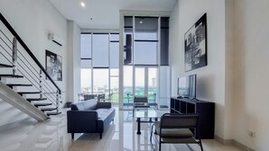 A modern living room with a staircase, a sofa, a coffee table, and a TV.
