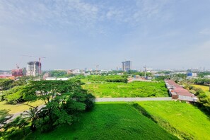 A cityscape with construction cranes, green fields, and buildings in the distance.