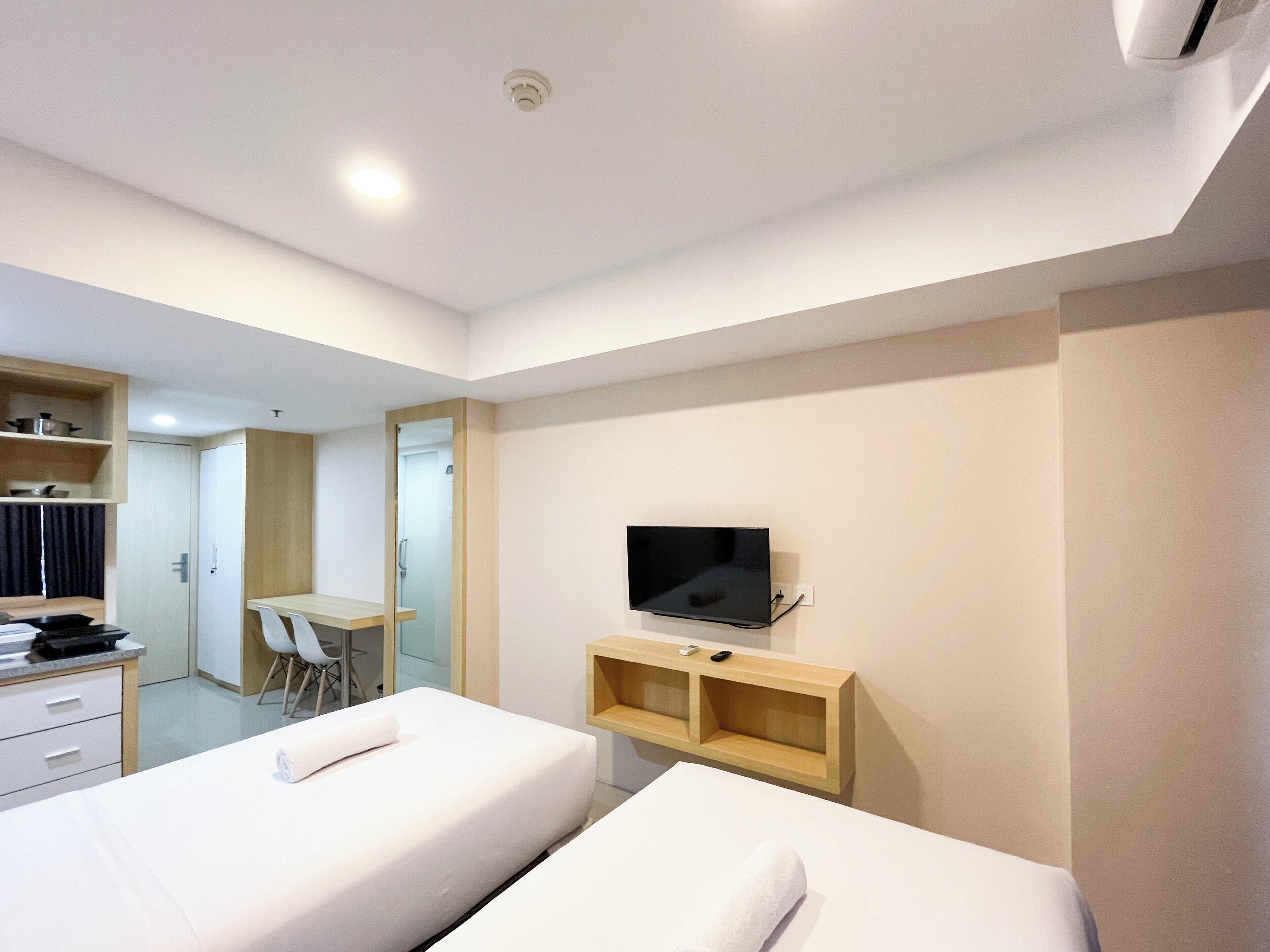 A hotel room with two beds, a desk, a TV, and a wardrobe.