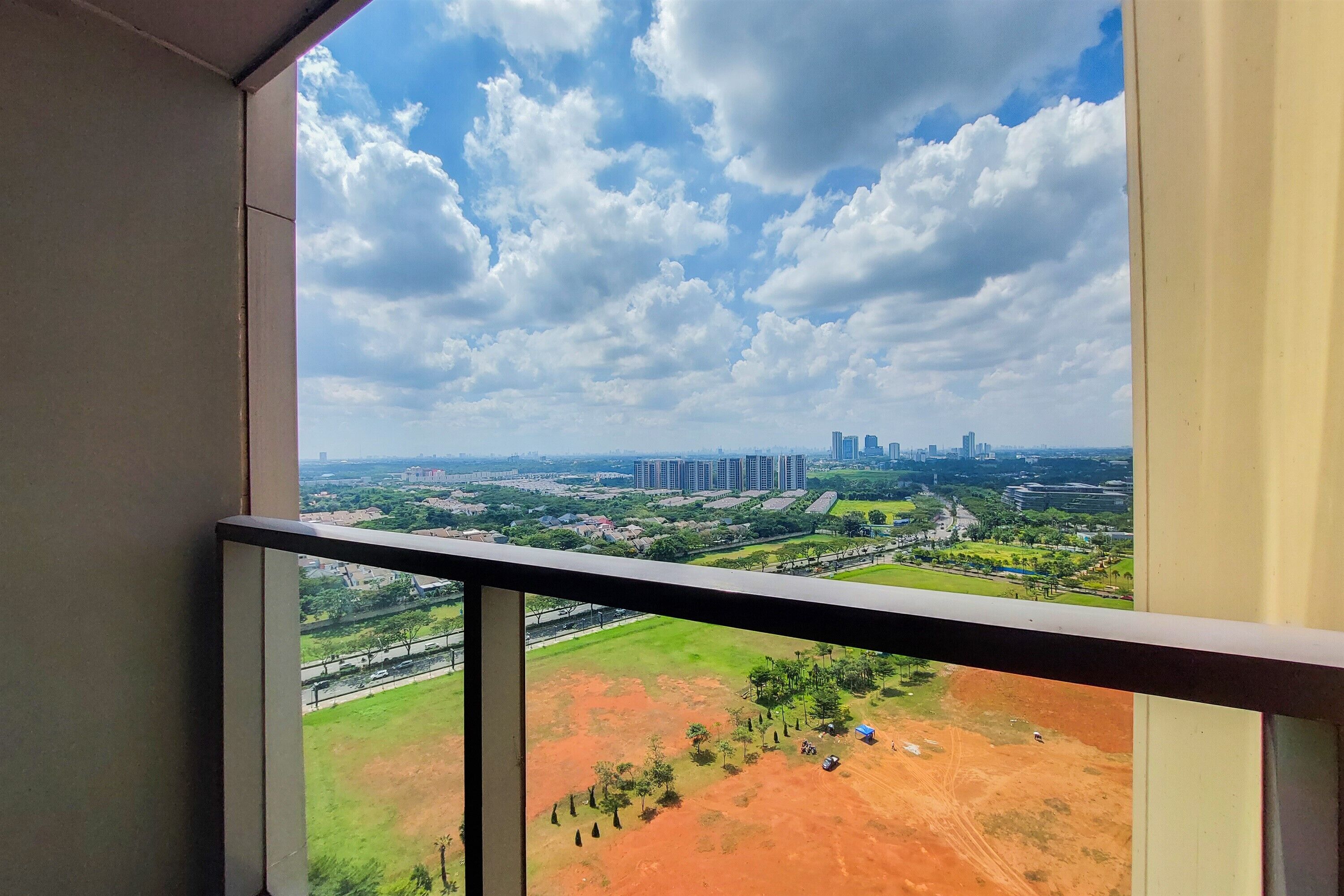 Un balcon offrant une vue sur le paysage urbain, avec ses bâtiments et sa végétation.