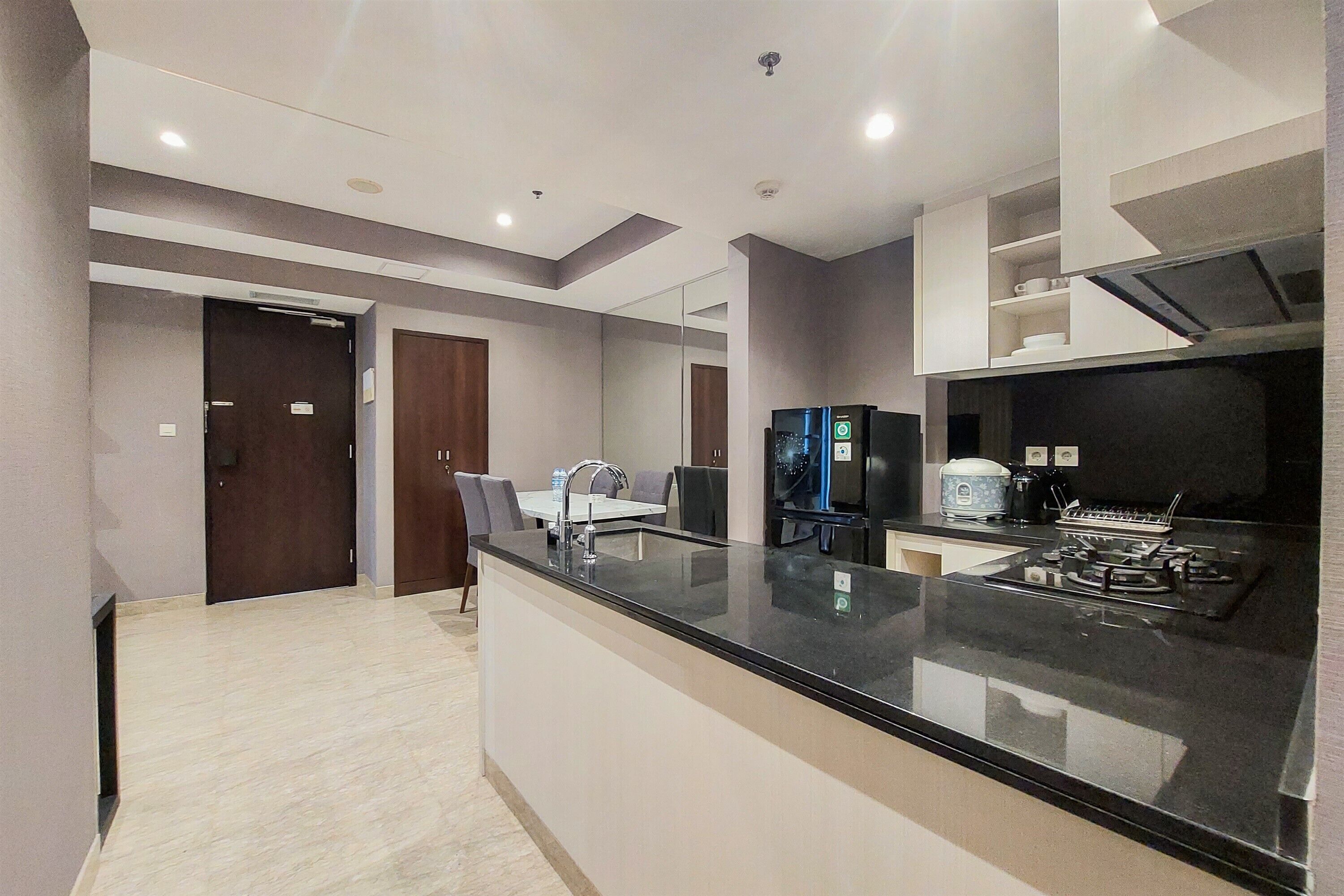 A modern kitchen with a black countertop, stainless steel appliances, and a dining area with a table and chairs.