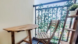 Una silla y una mesa de madera en un balcón con vistas a la ciudad.