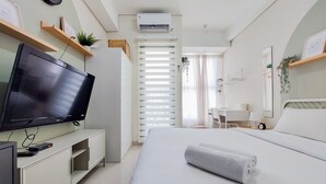 Una habitación de hotel con cama, televisión, escritorio y silla.