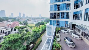 A modern building with multiple floors, large windows, and a rooftop garden with seating areas. - Spacious 2Br Loft At Brooklyn Alam Sutera Apartment (South Tangerang)