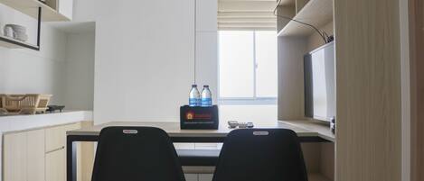 A modern kitchen with two black chairs, a dining table, and a box of travel essentials on the counter.