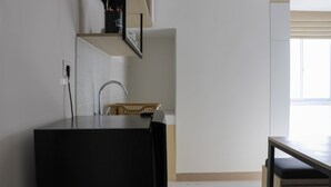 A kitchen with a black countertop, a wooden chair, and a window with blinds. - Restful And Cozy 2Br Tokyo Riverside Pik 2 Apartment (Teluknaga)