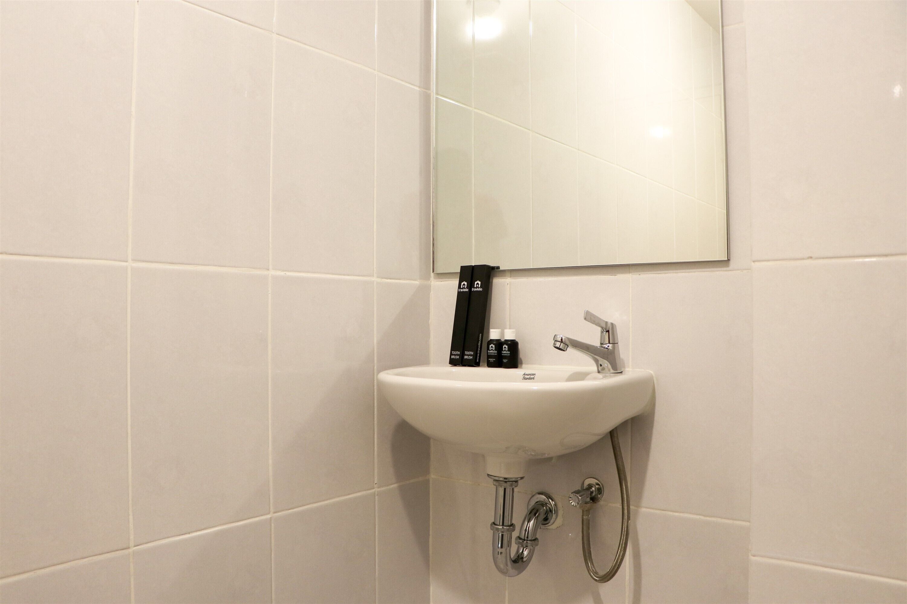 A bathroom with a white sink, a mirror, and a handheld showerhead.