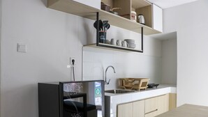 A modern kitchen with a built-in dishwasher, a sink, and wooden cabinets. - Restful And Cozy 2Br Tokyo Riverside Pik 2 Apartment (Teluknaga)