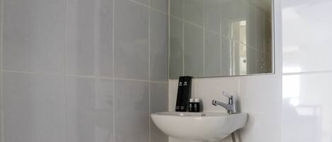 A bathroom with a white sink, a mirror, and a shower.