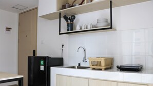 A modern kitchen with a black refrigerator, a sink, and wooden cabinets. - Restful And Cozy 2Br Tokyo Riverside Pik 2 Apartment (Teluknaga)