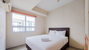 Une chambre d’hôtel avec un grand lit, une fenêtre donnant sur des immeubles et un ventilateur de plafond.