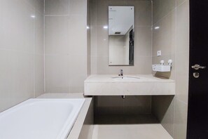 Ein modernes Badezimmer mit einer weißen Badewanne, einem Waschbecken mit Spiegel darüber und einer Toilette.
