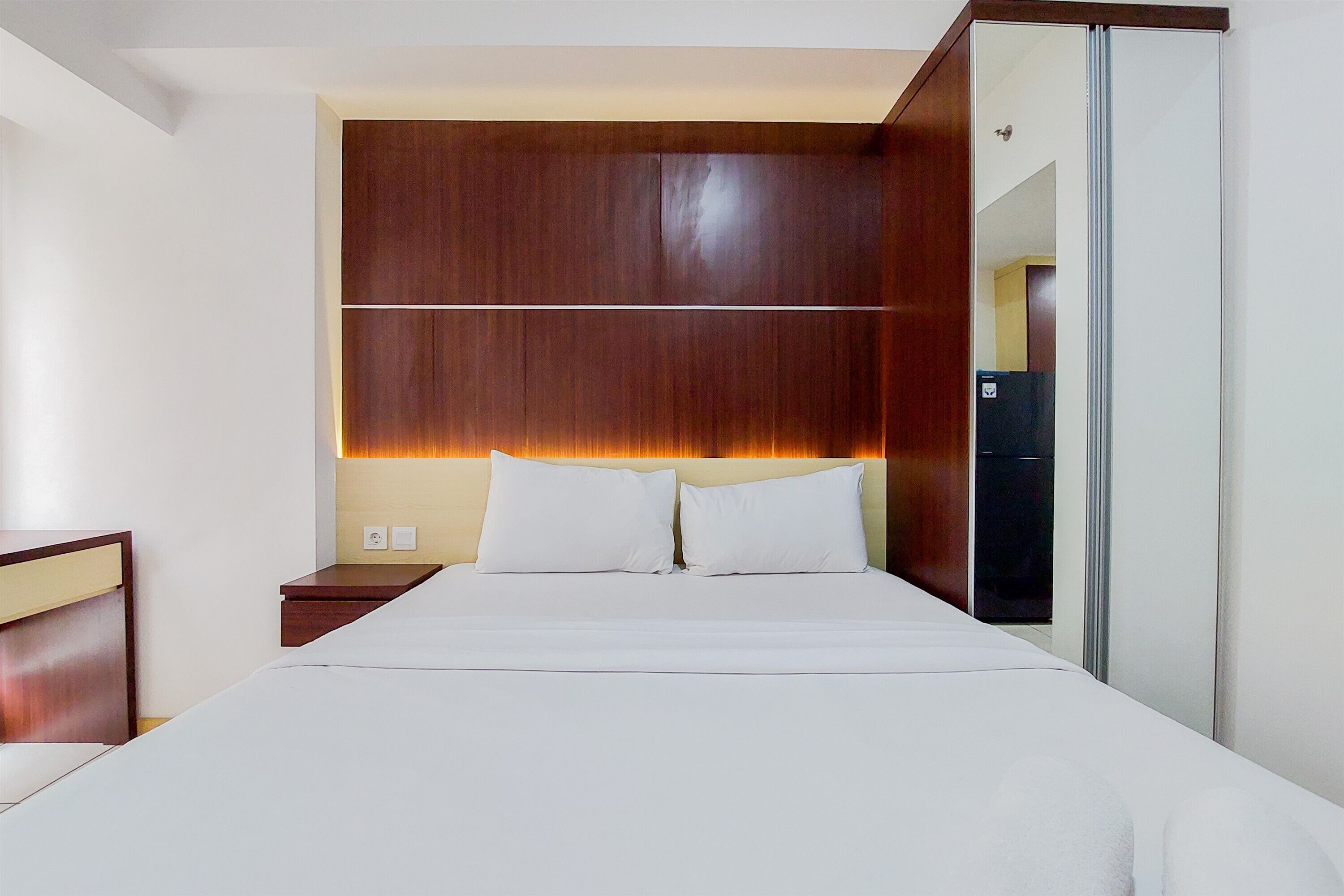 A hotel room with a large bed, wooden headboard, and a wardrobe with a mirror.
