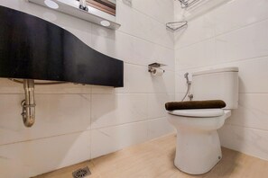 Ein Badezimmer mit einer weißen Toilette, einem schwarzen Waschbecken und einer Duschkabine.