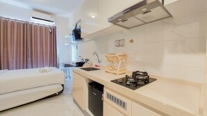 Une cuisine de taille réduite, équipée d’une cuisinière intégrée, d’un évier et d’un lave-vaisselle compact.