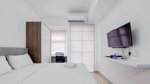 Een hotelkamer met een bed, een aan de muur bevestigde televisie, een airconditioning en een stoel.