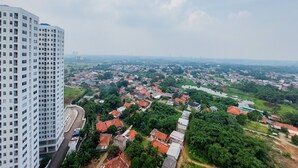 Een hoog gebouw naast een dichtbebouwd gebied met rode pannendaken en groen.