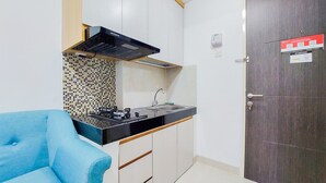A compact kitchen with a black stove, a tiled backsplash, and a wooden cabinet. - Best Deal And Comfortable 2Br Serpong Garden Apartment (Cisauk)