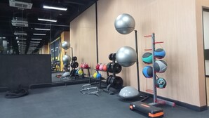 A gym with various exercise equipment, including kettlebells, dumbbells, and a step platform. - Spacious And Elegant 3Br Loft At Kingland Avenue Apartment (South Tangerang)