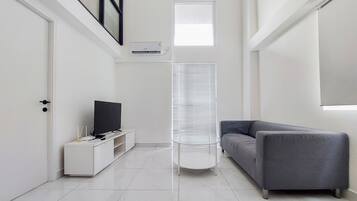 A modern living room with a grey sofa, a white entertainment unit, and a round table.