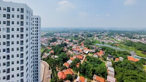 A high-rise building overlooking a densely populated area with red-roofed houses and a river. - Best Choice And Homey Studio Serpong Garden Apartment (Cisauk)