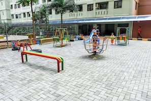 Children can play safely in this enclosed playground area, featuring swings, slides, and climbing frames.