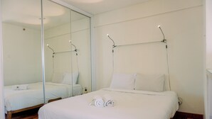 Camera d'albergo con due letti, un grande specchio e un pavimento in legno.