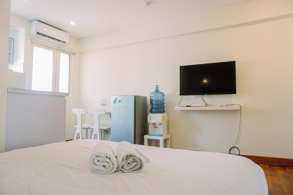 Une chambre d’hôtel équipée d’un lit, d’une télévision, d’un distributeur d’eau et d’un bureau avec une chaise.