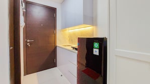 Una stanza con una porta in legno, un lavandino bianco e un frigorifero con un adesivo verde.