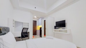 Una camera d'albergo con un letto, una scrivania, una sedia, una televisione e un armadio.