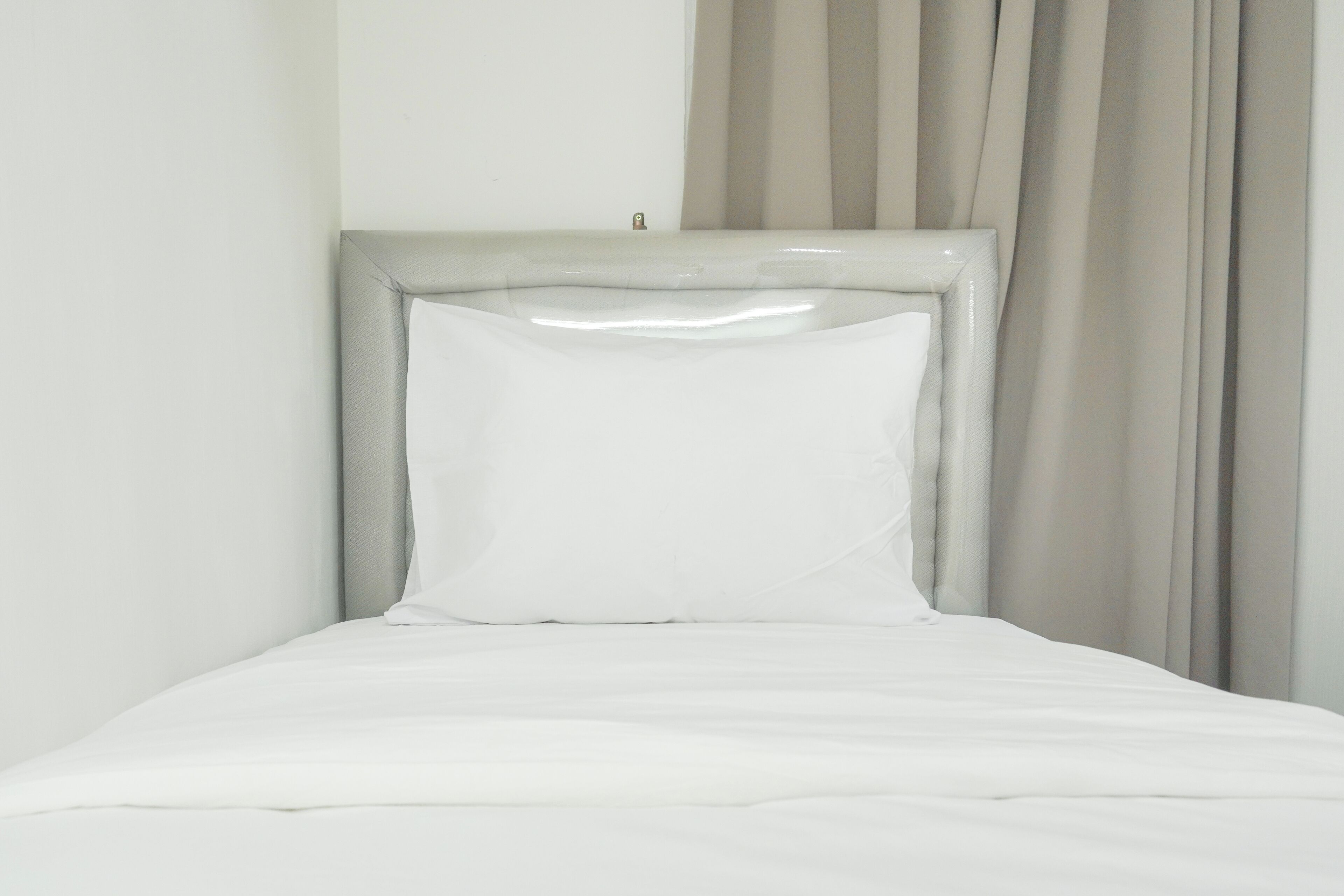 A bed with a white mattress and a headboard with a metallic frame.